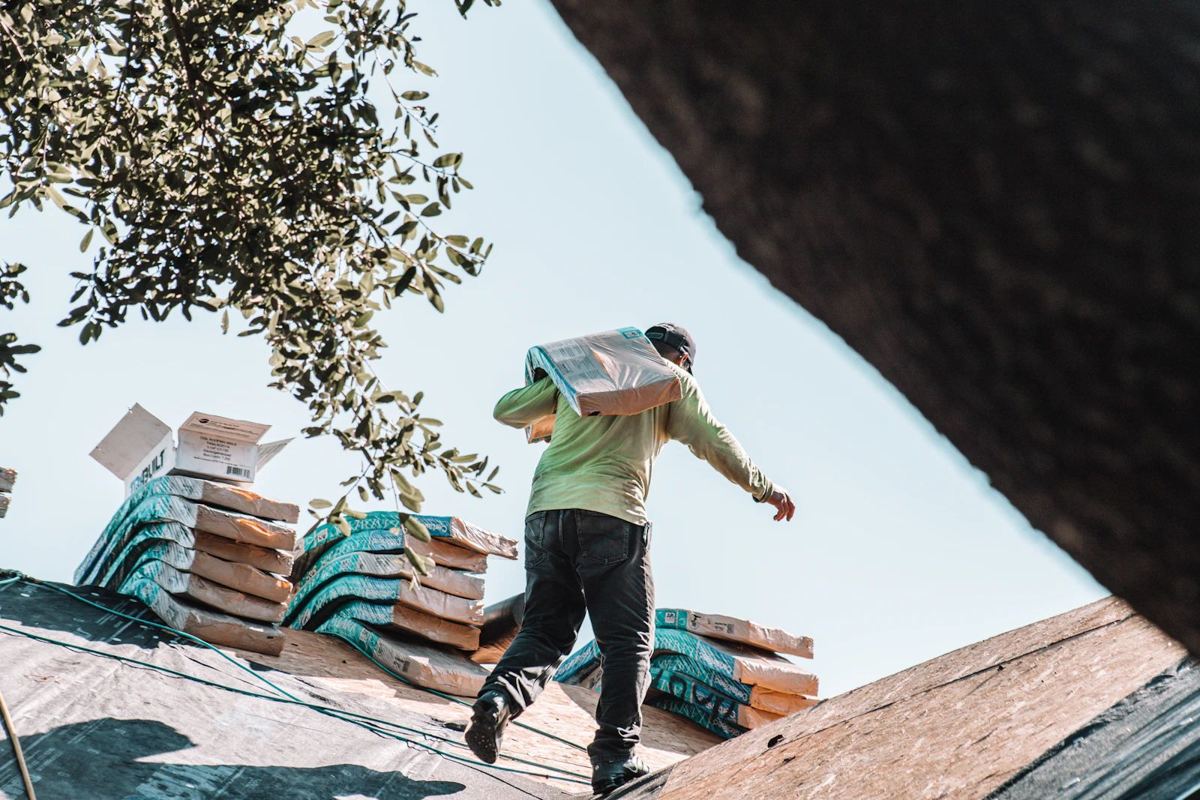 Roofer carrying shingles on a roof